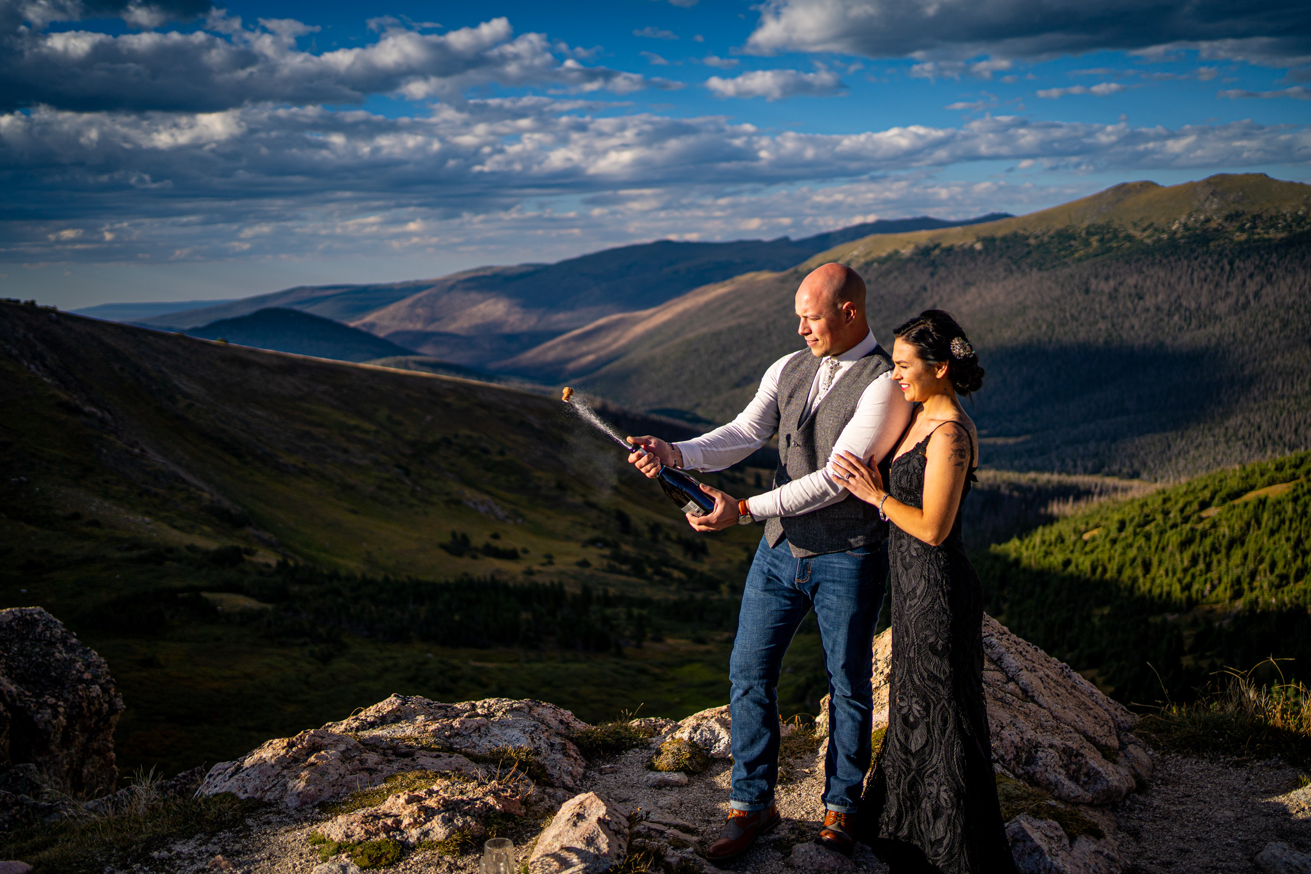 newlyweds celebrating with a bottle of champagne in rocky mountain national park, near estes park, colorado