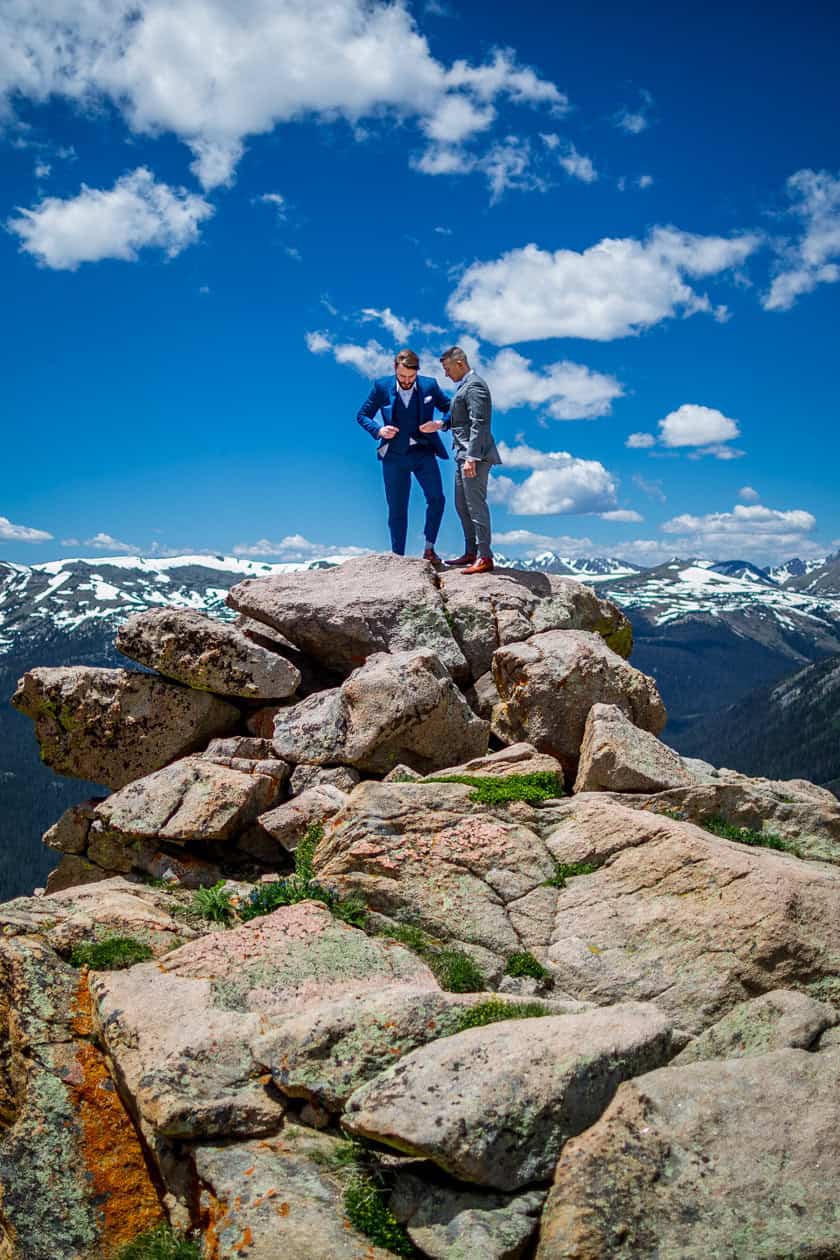 two gay men getting ready on a mountain top in rmnp